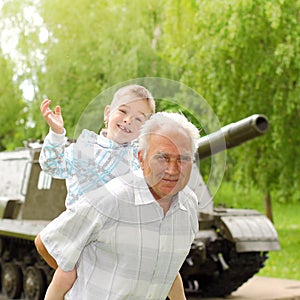 Grandfather and grandson are photographed on a background of vintage tank