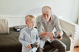 Grandfather and grandson playing video games on computer with joystick