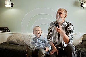 Grandfather and grandson playing video games on computer with joystick