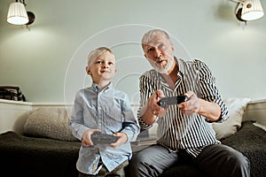 Grandfather and grandson playing video games on computer with joystick