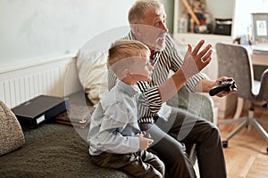 Grandfather and grandson playing video games on computer with joystick