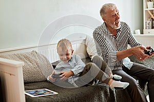 Grandfather and grandson playing video games on computer with joystick