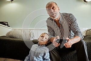 Grandfather and grandson playing video games on computer with joystick