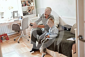 Grandfather and grandson playing video games on computer with joystick