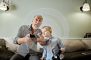 Grandfather and grandson playing video games on computer with joystick