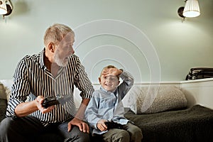 Grandfather and grandson playing video games on computer with joystick