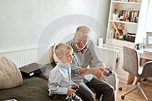 Grandfather and grandson playing video games on computer with joystick