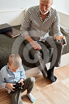 Grandfather and grandson playing video games on computer with joystick