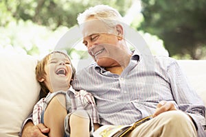 Abuelo nieto lectura común sobre el sofá 