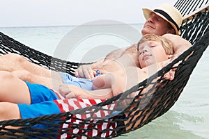 Grandfather And Grandson Relaxing In Beach Hammock