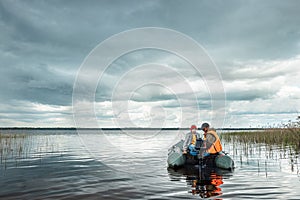 Grandfather and grandson ride a motor boat on the lake. The concept of family, summer vacation, generation. Copy space