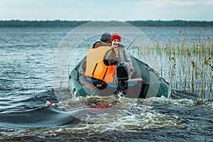 Grandfather and grandson ride a motor boat on the lake. The concept of family, summer vacation, generation. Copy space