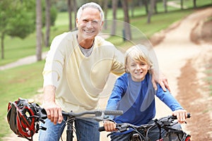 Grandfather and grandson riding bicycle in park