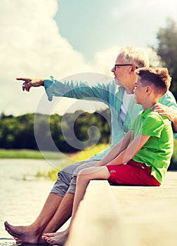 Grandfather and grandson sitting on river berth