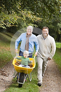 Grandfather with grandson and son pushing wheelbar