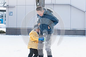 Grandfather and grandson walk in the park and make snowballs from the snow