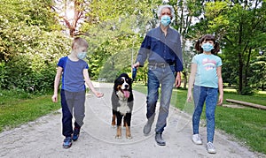 A grandfather and grandson are walking in the park with the dog during Coronavirus Pandemia