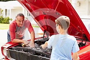 Grandfather And Grandson Working On Restored Classic Car