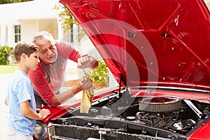 Grandfather And Grandson Working On Restored Classic Car