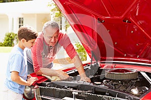 Grandfather And Grandson Working On Restored Classic Car