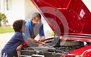 Grandfather And Grandson Working On Restored Classic Car