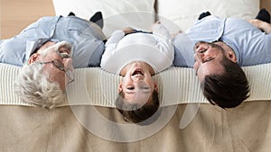 Grandfather grown up son grandson lies on bed heads down