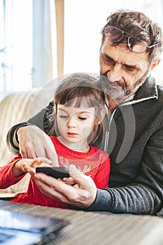 Grandfather helping his granddaughter with smartphone