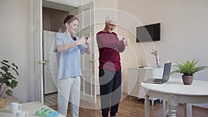 Grandfather and his adult daughter are engaged in exercises together. They use a fitness band