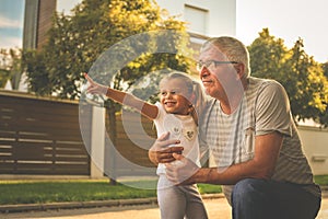 Grandfather with his granddaughter on street looking something fanny.