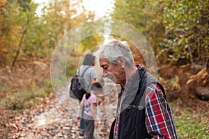 Grandfather with his grandson and granddaughter in the autumn forest, family hiking