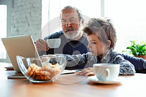 Grandfather and his grandson spending time insulated at home, stadying, watching cinema, shopping together