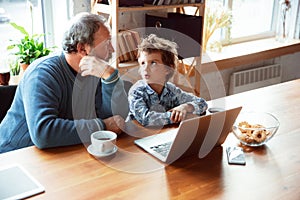 Grandfather and his grandson spending time insulated at home, stadying, watching cinema, shopping together