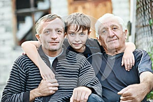 Grandfather with his son and grandson near country house