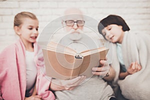 Grandfather holds a book in his hands.