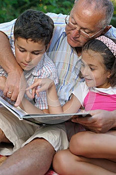 Grandfather and kids reading book