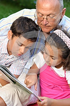 Grandfather and kids reading book