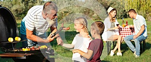 Grandfather with little kids cooking food on barbecue grill and their family in park. Banner design