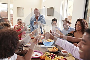 Grandfather making a toast standing at the dinner table celebrating with his family,close up