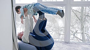 Grandfather are played with grandson lying on floor indoors