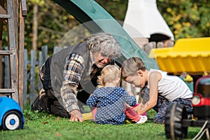 Grandfather playing with grandson and granddaughter outside on i