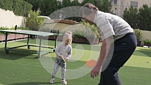 Grandfather plays table tennis with his little granddaughter