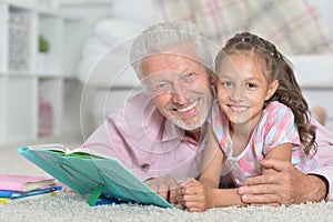 Grandfather reading book with his little granddaughter photo
