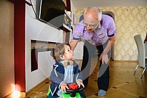 Grandfather rolls grandson in a toy car. redirection of grandfather and grandson. Happy weekend concept. Happy grandfather and photo