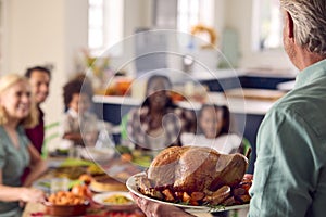 Grandfather Serving As Multi-Generation Family Celebrating Thanksgiving At Home Eating Meal Together