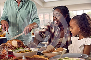 Grandfather Serving As Multi-Generation Family Celebrating Thanksgiving At Home Eating Meal Together