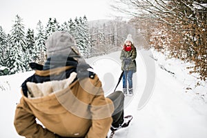 Grandfather and small girl sledging on a winter day.