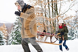 Grandfather and small girl in snow on a winter day.