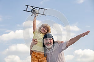 Grandfather and son playing with toy airplane against summer sky background. Weekend with granddad.
