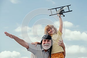 Grandfather and son playing with toy airplane against summer sky background. Weekend with granddad.