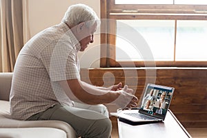 Grandfather talking with friends using pc webcam and videoconference app